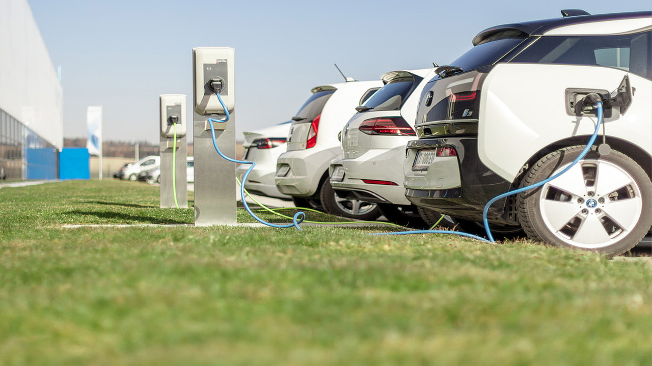 parkende Elektroautos an Ladestation auf grünem Rasen 