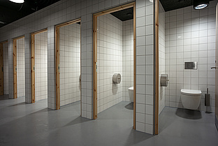 WC-Kabinen mit weißen Kacheln und Toiletten 