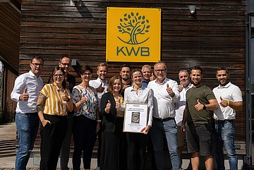KWB Geschäftsführer mit Auszeichnung und Mitarbeitern vor Firmenlogo 