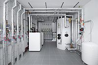 weiße Luft-Wärmepumpe in Keller und aluminiumverkleidete Rohre 