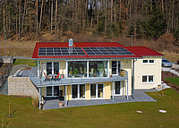 großes Einfamilienhaus mit Photovoltaik-Anlage auf rotem Ziegeldach