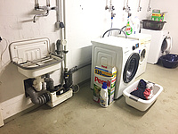Waschmaschine in Kellerraum neben Spültisch und Trockner