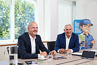 Thomas Stadlhofer und Dragan Skrebic sitzen an Tisch und lächeln