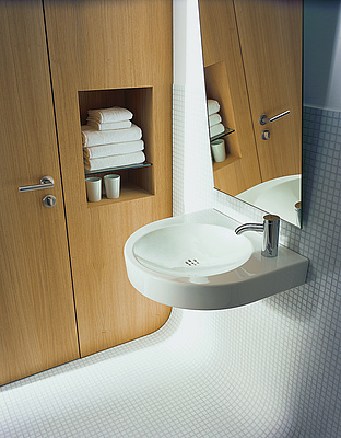 weißes Waschbecken mit Spiegel vor braunem Schrank 